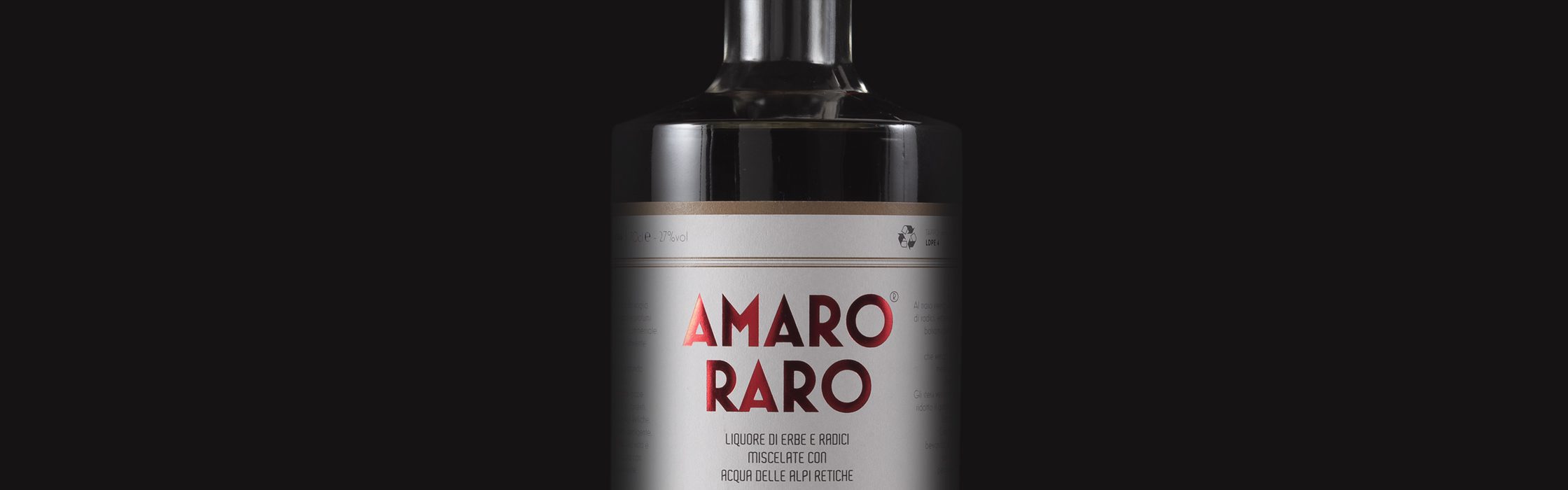 Bottiglia di Amaro Raro, liquore artigianale italiano con erbe aromatiche e acqua delle Alpi Retiche, su fondo nero per homepage.